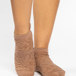 Woman wearing a tan full foot grip sock with a raised macaroni terry pattern, made for pilates, barre, yoga, and beyond.  