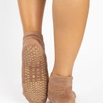 Woman wearing a tan full foot grip sock with a raised macaroni terry pattern, made for pilates, barre, yoga, and beyond.  