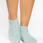 Woman wearing a light blue full foot grip sock with a raised macaroni terry pattern, made for pilates, barre, yoga, and beyond.  