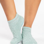 Woman wearing a light blue full foot grip sock with a raised macaroni terry pattern, made for pilates, barre, yoga, and beyond.  