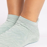 Woman wearing a light blue full foot grip sock with a raised macaroni terry pattern, made for pilates, barre, yoga, and beyond.  