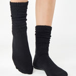 Women wearing a black mid-weight knit grip sock that scrunches, made for Pilates, Barre, Yoga, and Beyond. 