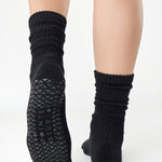 Women wearing a black mid-weight knit grip sock that scrunches, made for Pilates, Barre, Yoga, and Beyond. 