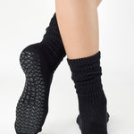 Women wearing a black mid-weight knit grip sock that scrunches, made for Pilates, Barre, Yoga, and Beyond. 