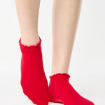 Women wearing a solid bright red full foot grip sock with a playful ruffle cuff made for Pilates, Barre, Yoga, and Beyond. 