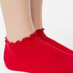 Women wearing a solid bright red full foot grip sock with a playful ruffle cuff made for Pilates, Barre, Yoga, and Beyond. 