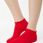 Women wearing a solid bright red full foot grip sock with a playful ruffle cuff made for Pilates, Barre, Yoga, and Beyond. 