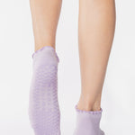 Women wearing a solid light purple full foot grip sock with a playful ruffle cuff made for Pilates, Barre, Yoga, and Beyond. 