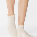 Women wearing a solid white full foot grip sock with a playful ruffle cuff made for Pilates, Barre, Yoga, and Beyond. 