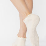 Women wearing a solid white full foot grip sock with a playful ruffle cuff made for Pilates, Barre, Yoga, and Beyond. 