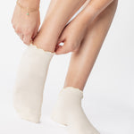 Women wearing a solid white full foot grip sock with a playful ruffle cuff made for Pilates, Barre, Yoga, and Beyond. 