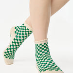Woman wearing a green with beige ankle grip sock with a ruffled cuff made for Pilates, Barre, Yoga, and beyond. 
