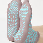 Woman wearing a checkered light blue with gray ankle grip sock with a ruffled cuff made for Pilates, Barre, Yoga, and beyond. 
