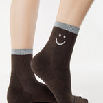 Women wearing brown ankle grip socks with white happy face and reflective stripe for running. 