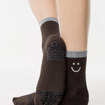 Women wearing brown ankle grip socks with white happy face and reflective stripe for running. 