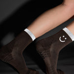 Women wearing brown ankle grip socks with white happy face and reflective stripe for running. 