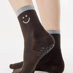 Women wearing brown ankle grip socks with white happy face and reflective stripe for running. 