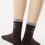 Women wearing brown ankle grip socks with white happy face and reflective stripe for running. 