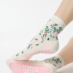 Woman wearing a white ankle grip sock with green rose vines and pink flowers made for Pilates, Barre, Yoga, and beyond.