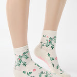 Woman wearing a white ankle grip sock with green rose vines and pink flowers made for Pilates, Barre, Yoga, and beyond.