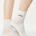 Women wearing a solid white ankle grip sock with "don't slip" on the ankle made for Pilates, Barre, Yoga, and beyond. 