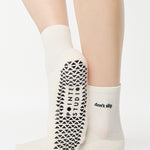 Women wearing a solid white ankle grip sock with "don't slip" on the ankle made for Pilates, Barre, Yoga, and beyond. 