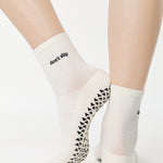 Women wearing a solid white ankle grip sock with "don't slip" on the ankle made for Pilates, Barre, Yoga, and beyond. 