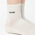 Women wearing a solid white ankle grip sock with "don't slip" on the ankle made for Pilates, Barre, Yoga, and beyond. 