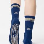 Woman wearing a navy blue crew grip sock with "keep going" embroidered in the back part of the ankle/calf area, made for Pilates, Barre, Yoga, and beyond. 