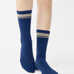 Woman wearing a navy blue crew grip sock with "keep going" embroidered in the back part of the ankle/calf area, made for Pilates, Barre, Yoga, and beyond. 