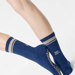 Woman wearing a navy blue crew grip sock with "keep going" embroidered in the back part of the ankle/calf area, made for Pilates, Barre, Yoga, and beyond. 