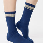 Woman wearing a navy blue crew grip sock with "keep going" embroidered in the back part of the ankle/calf area, made for Pilates, Barre, Yoga, and beyond. 