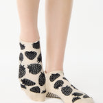 Women wearing a white full foot grip sock with black strawberries all around. 