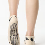 Women wearing a white full foot grip sock with black strawberries all around. 