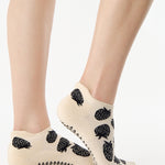 Women wearing a white full foot grip sock with black strawberries all around. 