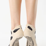 Women wearing a white full foot grip sock with black strawberries all around. 