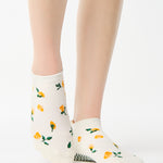 Women wearing a white full foot grip sock with little yellow flowers all around. 