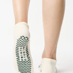 Women wearing a white full foot grip sock with little yellow flowers all around. 