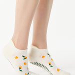Women wearing a white full foot grip sock with little yellow flowers all around. 