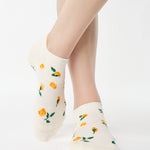 Women wearing a white full foot grip sock with little yellow flowers all around. 
