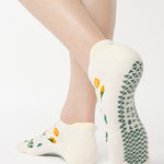 Women wearing a white full foot grip sock with little yellow flowers all around. 