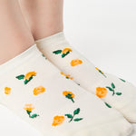 Women wearing a white full foot grip sock with little yellow flowers all around. 