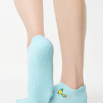 Women wearing a light blue full foot grip sock with a yellow lemon motif near the cuff made for Pilates, Barre, Yoga, and beyond. 