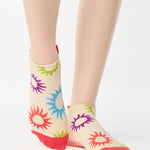 Women wearing an off white full foot grip sock with colorful suns all around made for pilates, yoga, barre, and beyond.