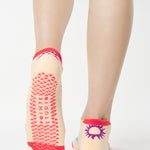 Women wearing an off white full foot grip sock with colorful suns all around made for pilates, yoga, barre, and beyond.