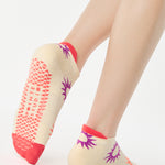 Women wearing an off white full foot grip sock with colorful suns all around made for pilates, yoga, barre, and beyond.