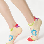 Women wearing an off white full foot grip sock with colorful suns all around made for pilates, yoga, barre, and beyond.