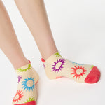 Women wearing an off white full foot grip sock with colorful suns all around made for pilates, yoga, barre, and beyond.