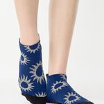 Women wearing a navy full foot grip sock with white suns all around made for pilates, yoga, barre, and beyond.