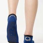 Women wearing a navy full foot grip sock with white suns all around made for pilates, yoga, barre, and beyond.